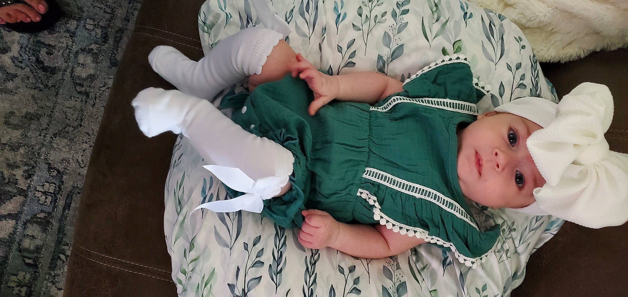 Evelynn is registered to the contest to win money with this photo: arm, baby, baby_products, baby_toddler_clothing, child, comfort, finger, hand, headwear, human_body, leg, linens, pattern, person, sitting, sleeve, sock, thigh, toddler, tree