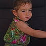 Nora a rejoint le concours — aidez-le/la à gagner de superbes lots ! child, girl, floral_dress, serious_expression, sitting, dark_background, brown_hair, earrings, portrait, cute, young_child, side_view, looking_away, colorful_clothing, indoors, person, youth, small_child, focused, casual_clothing