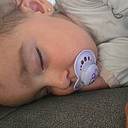 Nora a rejoint le concours — aidez-le/la à gagner de superbes lots ! child, sleeping, pacifier, face, hand, pajamas, bedtime, closeup, rest, peaceful, young, indoors, comfort, soft, hair, earring, relaxation, skin, nap, cozy