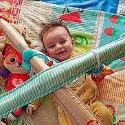 Mickaël participe au concours pour gagner de l'argent avec cette photo : baby, smiling, play_gym, plush_toy, colorful, toddler, indoor, child, happy, face, toy, blanket, fabric, pattern, cute, infant, lying_down, soft_toy, playtime, home