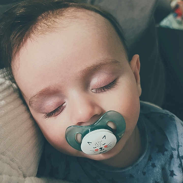 Mickaël a rejoint le concours — aidez-le/la à gagner de superbes lots ! toddler, sleeping, pacifier, child, face, closed_eyes, blanket, pillow, cozy, indoor, soft_lighting, cute, rest, peaceful, baby_clothes, hair, comfort, nap, relaxation, portrait
