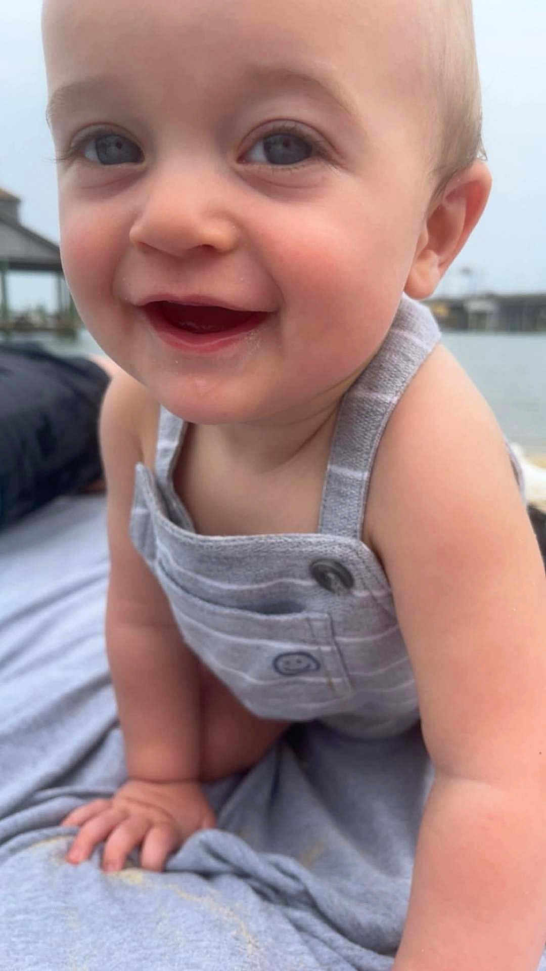 Slater joined the competition — help win amazing prizes! baby, child, smiling, close_up, romper, blue_eyes, skin, arm, hand, outdoor, water, background_blur, happy, infant, cute, person, portrait, clothing, head, face