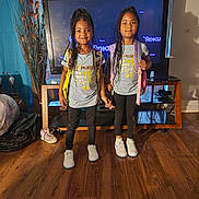 Destiny joined the competition — help win amazing prizes! child, children, girls, siblings, matching_outfits, backpacks, smiling, indoor, living_room, television, wood_floor, casual_clothing, braided_hair, shoes, home, furniture, happy, person, portrait, together