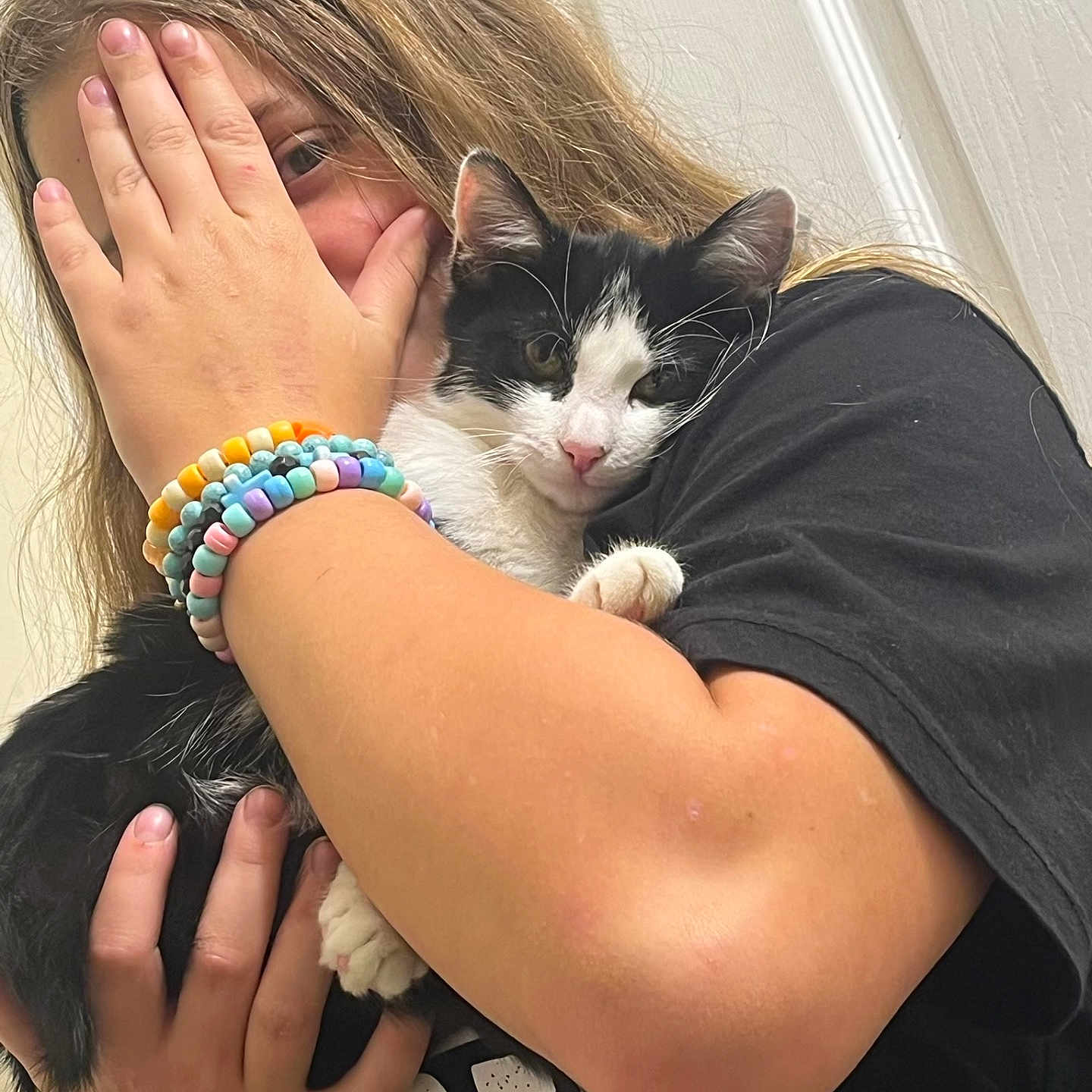 Divine is registered to the contest to win money with this photo: animal, black_and_white_cat, black_shirt, bracelets, cat, close_up, companionship, cozy, cuddling, ears, fur, hand, hugging, indoor, person, pet, pink_nose, portrait, smiling, whiskers