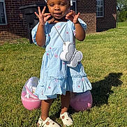De' Azhia is registered to the contest to win money with this photo: child, toddler, girl, blue_dress, outdoor, grass, sunny, shoes, bag, butterfly, pose, playful, smile, hair_beads, brick_house, window, shadow, plastic_egg, toy, accessory