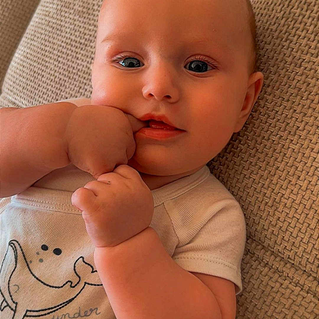 Lèven a rejoint le concours — aidez-le/la à gagner de superbes lots ! adorable, baby, baby_smile, cheek, child, close_up, clothing, couch, eyes, fabric_texture, face, fingers, hand, indoor, infant, lying_down, mouth, onesie, portrait, skin