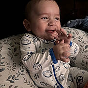 Michael Xavier Weems is registered to the contest to win money with this photo: baby, child, clapping, comfort, cozy, cushion, cute, hand_gesture, happy, indoor, infant, leaf_pattern, onesie, person, portrait, seated, smiling, soft_lighting, sports_pattern, young