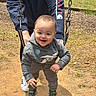 Jaden is registered to the contest to win money with this photo: toddler, child, swing, playground, outdoor, smiling, hoodie, sneakers, adult, person, grass, dirt, sunny, park, casual_clothing, joy, fun, recreation, happiness, activity