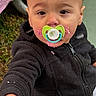 Jaden is registered to the contest to win money with this photo: toddler, child, pacifier, messy_face, black_jacket, outdoor, grass, cake, frosting, hand, face, curious, young_child, portrait, person, clothing, cute, messy, baby, expression