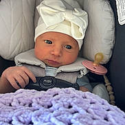 Laneigha is registered to the contest to win money with this photo: baby, infant, car_seat, hat, bow, blanket, purple, hand, face, eyes, clothing, seatbelt, pacifier, soft, cute, newborn, closeup, portrait, indoors, baby_accessory