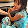 Nacho is registered to the contest to win money with this photo: child, girl, dog, pug, princess_dress, smiling, hugging, indoor, portrait, pet, animal, wrinkled_face, seated, turquoise, dress, family, happy, playful, furniture, home