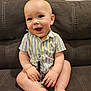 baby, child, infant, smiling, couch, sofa, striped_shirt, sitting, hands, feet, toes, pacifier_clip, face, eyes, mouth, legs, adorable, home_interior, furniture, portrait