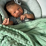 Silas joined the competition — help win amazing prizes! newborn, baby, blanket, cushion, plush_toy, infant, seat, striped_clothing, hand, face, curious_expression, soft_texture, indoors, child, resting, baby_boy, newborn_baby, comfort, infant_care, cute