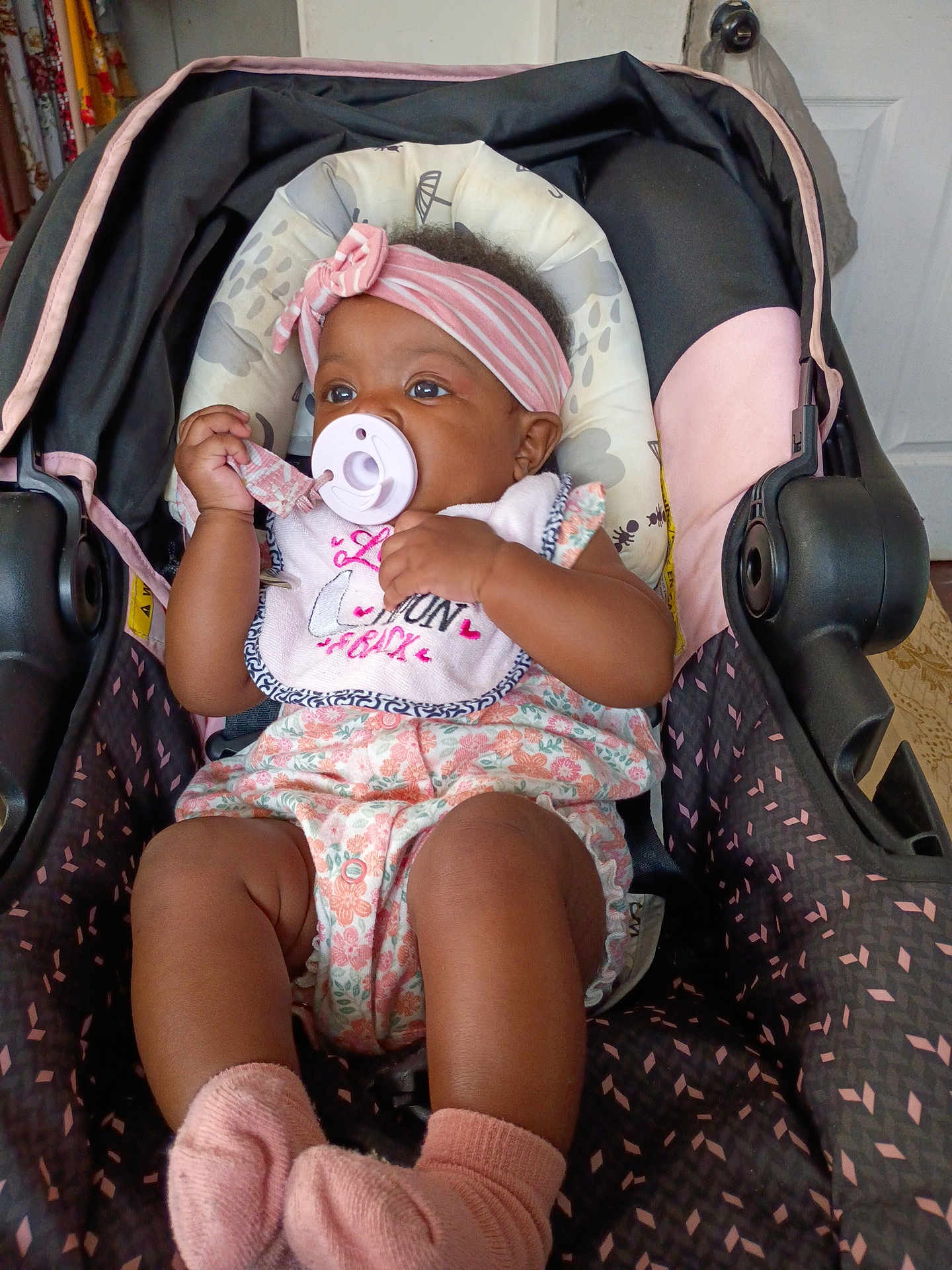 K'La joined the competition — help win amazing prizes! baby, infant, pacifier, headband, stroller, pink_socks, floral_outfit, child, cute, indoors, seat, comfort, portrait, young_child, clothing, baby_accessory, relaxing, small_person, adorable, baby_bib