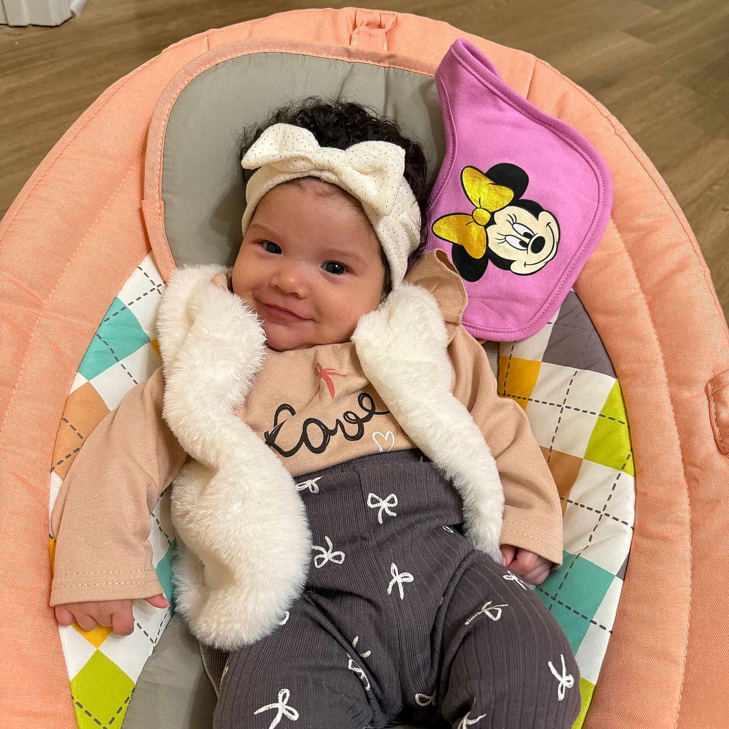 Amaia joined the competition — help win amazing prizes! baby, bib, child, clothing, cushion, cute, floor, happy, headband, indoor, infant, minnie_mouse, patterned_pants, person, pink, portrait, seat, smile, vest, wooden_floor