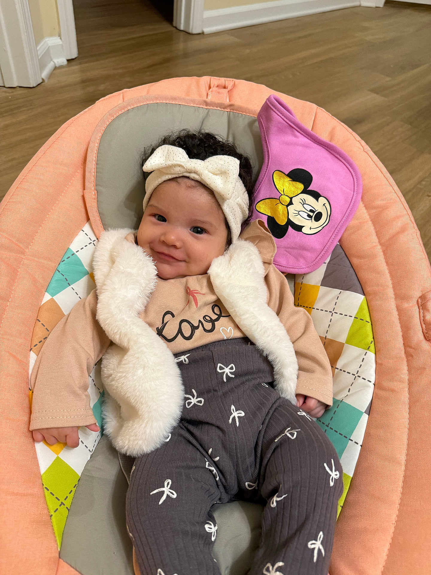 Amaia joined the competition — help win amazing prizes! baby, infant, smile, headband, vest, bib, minnie_mouse, pink, cushion, seat, floor, wooden_floor, clothing, patterned_pants, cute, child, indoor, portrait, happy, person