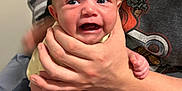 Maylin is registered to the contest to win money with this photo: baby, infant, crying, hand, person, skin, face, expression, holding, torso, clothing, shorts, adult, arm, leg, foot, fingers, indoor, closeup, portrait
