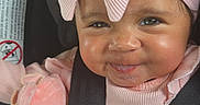 Ava joined the competition — help win amazing prizes! baby, car_seat, child, closeup, curly_hair, cute, face, happy, headband, indoor, infant, person, pink_bow, pink_clothing, plush_toy, portrait, safety_belt, seatbelt, smile, soft_toy