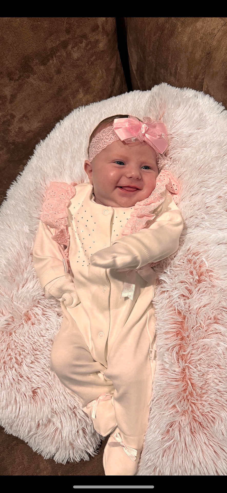 Navi is registered to the contest to win money with this photo: baby, infant, smile, headband, bow, blanket, soft_texture, pink, cream_outfit, lace, mittens, footed_pajamas, couch, cozy, happy, portrait, child, cute, indoors, relaxed