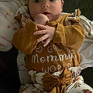 Paisley is registered to the contest to win money with this photo: baby, infant, headband, clothing, blanket, cute, face, hands, indoor, child, person, patterned_pants, brown, white, soft, portrait, lying_down, adorable, cozy, young
