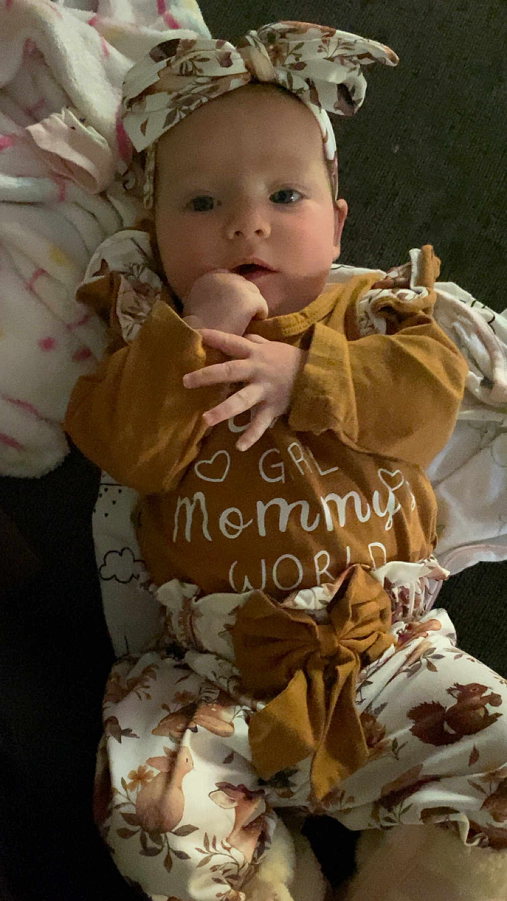 Paisley is registered to the contest to win money with this photo: baby, infant, headband, clothing, blanket, cute, face, hands, indoor, child, person, patterned_pants, brown, white, soft, portrait, lying_down, adorable, cozy, young