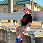 Porter joined the competition — help win amazing prizes! child, boy, bench, cap, red_shoes, spiderman, outdoor, daylight, concrete, building, shorts, tshirt, sitting, side_view, solemn, metal_bench, sunlight, casual_clothing, young, waiting