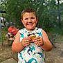 Levi is registered to the contest to win money with this photo: child, boy, smile, s'more, campfire, forest, tank_top, sharks, outdoor, happy, summer, food, snack, nature, person, daytime, recreation, fun, blurred_background, family