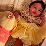 baby, infant, smiling, yellow_dress, headband, plush_toy, winnie_the_pooh, blanket, cute, lying_down, child, indoors, happy, soft_toy, patterned_clothing, feet, hand, portrait, adorable, cozy
