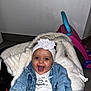 Mayannah participe au concours pour gagner de l'argent avec cette photo : baby, smiling, denim_jacket, headband, flower, blanket, stroller, indoor, toy, happy, child, cute, clothing, person, face, infant, joyful, cozy, white, blue