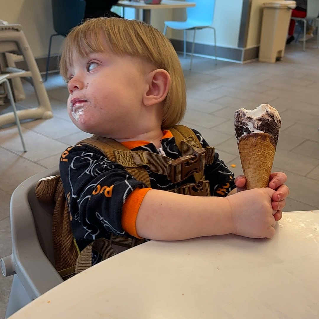 Lucas is registered to the contest to win money with this photo: adult, art, boy, child, cream, dessert, face, female, food, furniture, head, icecream, icing, male, man, painting, person, sitting, softserveicecream, woman