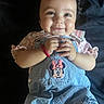 Alaiyah is registered to the contest to win money with this photo: baby, child, smiling, denim_overalls, minnie_mouse_patch, pink_hair_clip, pony_tail, happy, infant, cute, clothing, hands, face, portrait, lying_down, dark_background, skin, eyes, person, casual