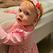 Amara joined the competition — help win amazing prizes! toddler, child, pink_dress, headband, heart_pattern, indoors, bed, curious, face, portrait, person, young_child, soft_lighting, bedroom, clothing, hair, skin, expression, standing, holding