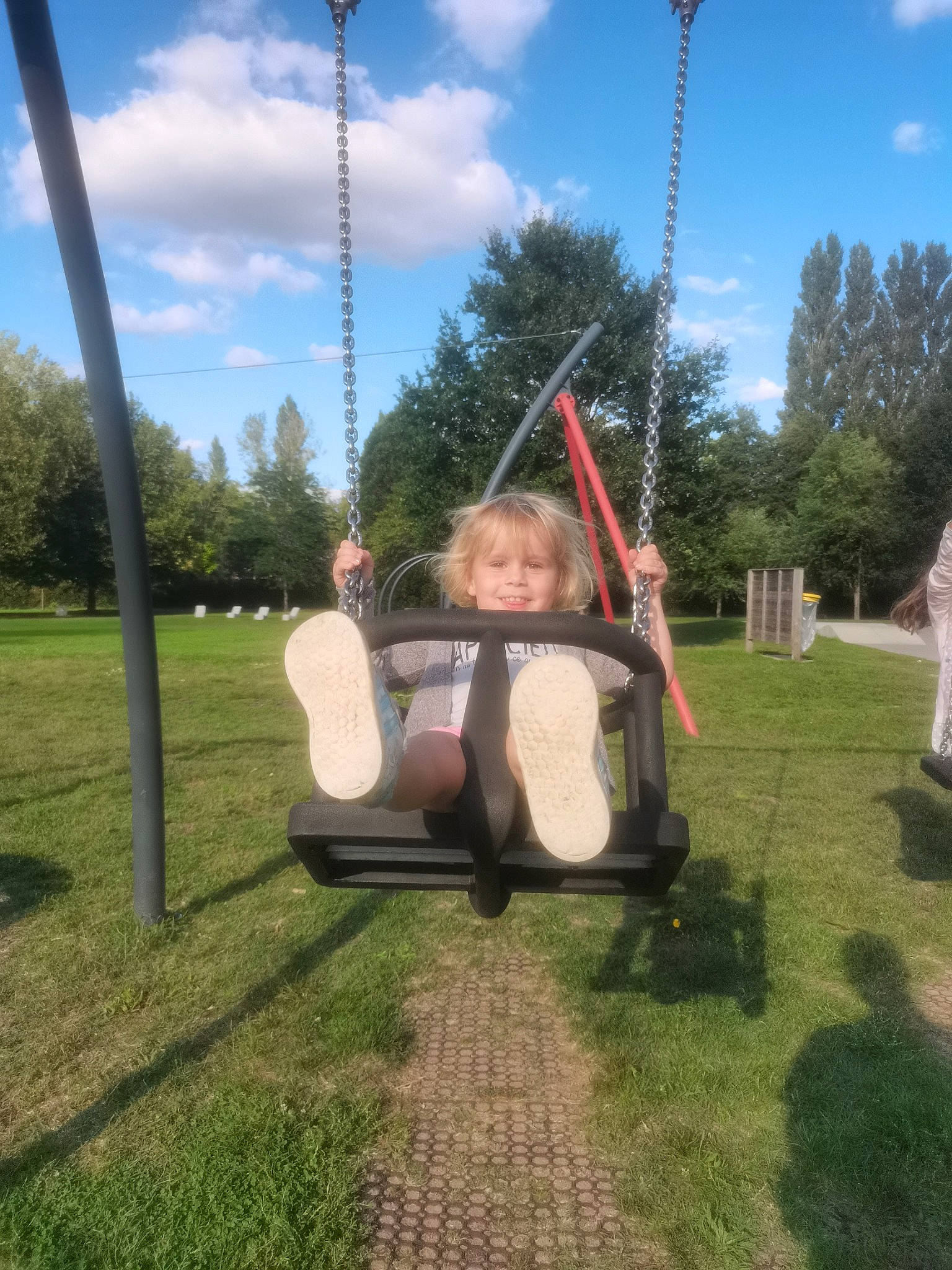 Lyna participe au concours pour gagner de l'argent avec cette photo : baby, child, city, cloud, fun, grass, joy, leisure, outdoor_play_equipment, person, plant, playground, pole, recreation, shade, sitting, sky, smile, swing, toddler
