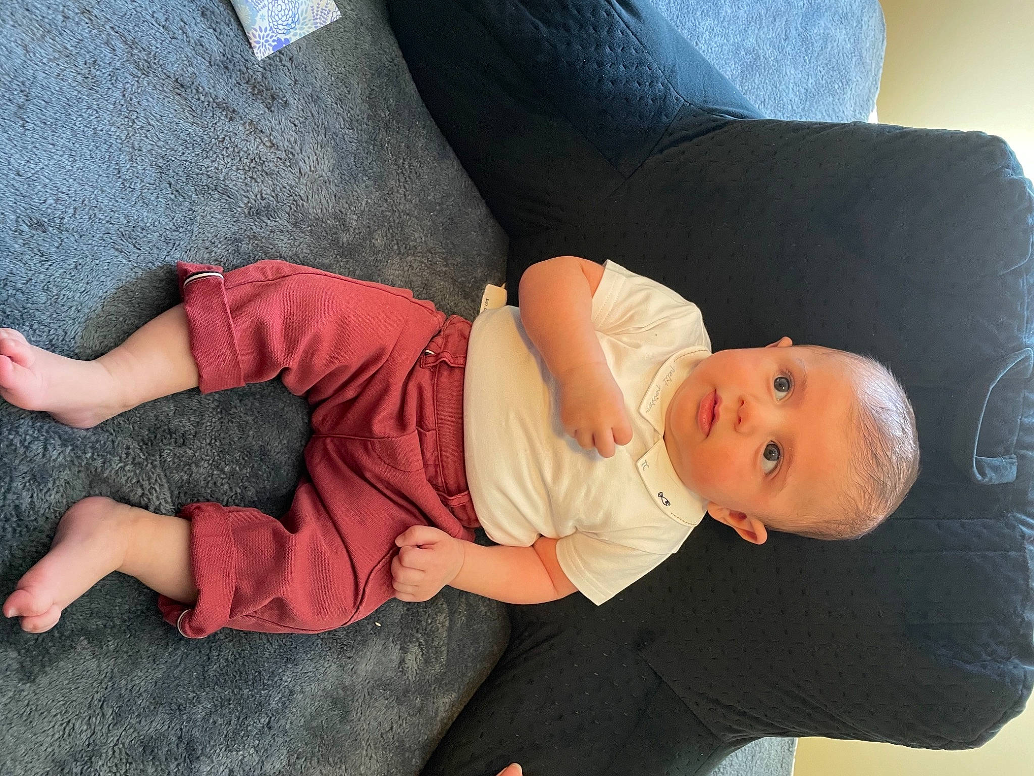 Eddie is registered to the contest to win money with this photo: baby, baby_toddler_clothing, barefoot, child, comfort, elbow, finger, foot, gesture, human_body, human_leg, knee, lap, leg, person, sitting, skin, sleeve, sock, thigh