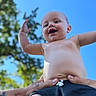 Wylder is registered to the contest to win money with this photo: baby, child, smiling, arms_up, outdoor, blue_sky, tree, tattooed_hand, holding, happiness, skin, shorts, person, summer, nature, sunlight, portrait, cute, joy, playful