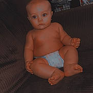 Wylder is registered to the contest to win money with this photo: baby, background, child, chubby, couch, curious, diaper, expression, face, foot, furniture, hand, head, household, indoor, infant, red_eye, room, sitting, skin