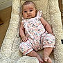 baby, baby_nest, child, comfortable, cozy, curious_expression, cute, floral_clothing, indoor, infant, newborn, plush, portrait, romper, sitting, skin, small_feet, small_hands, soft_texture, wooden_floor