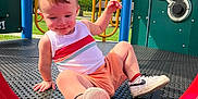 Dayton is registered to the contest to win money with this photo: toddler, child, playground, slide, outdoor, summer, tree, blue_sky, sneakers, tank_top, shorts, play_equipment, happy, fun, daylight, grass, park, metal_platform, yellow_rails, red_slide
