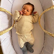 Ulysse a rejoint le concours — aidez-le/la à gagner de superbes lots ! newborn, baby, infant, bassinet, knitted_clothing, cream_color, gray_booties, cozy, cute, sleeping_area, soft_fabric, wooden_floor, indoors, resting, baby_fashion, portrait, small_hands, baby_booties, relaxing, child