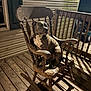 dog, rocking_chair, porch, wooden_floor, night, shadow, light, wooden_railing, house_siding, pet, animal, sitting, brown_dog, white_chest, outdoor, quiet, peaceful, calm, looking_away, vintage_furniture