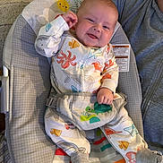Bentley is registered to the contest to win money with this photo: baby, infant, child, onesie, smile, happy, baby_seat, cushion, sock_slippers, adult_arm, indoor, colorful, playful, cute, comfort, clothing, person, portrait, baby_toys, fun