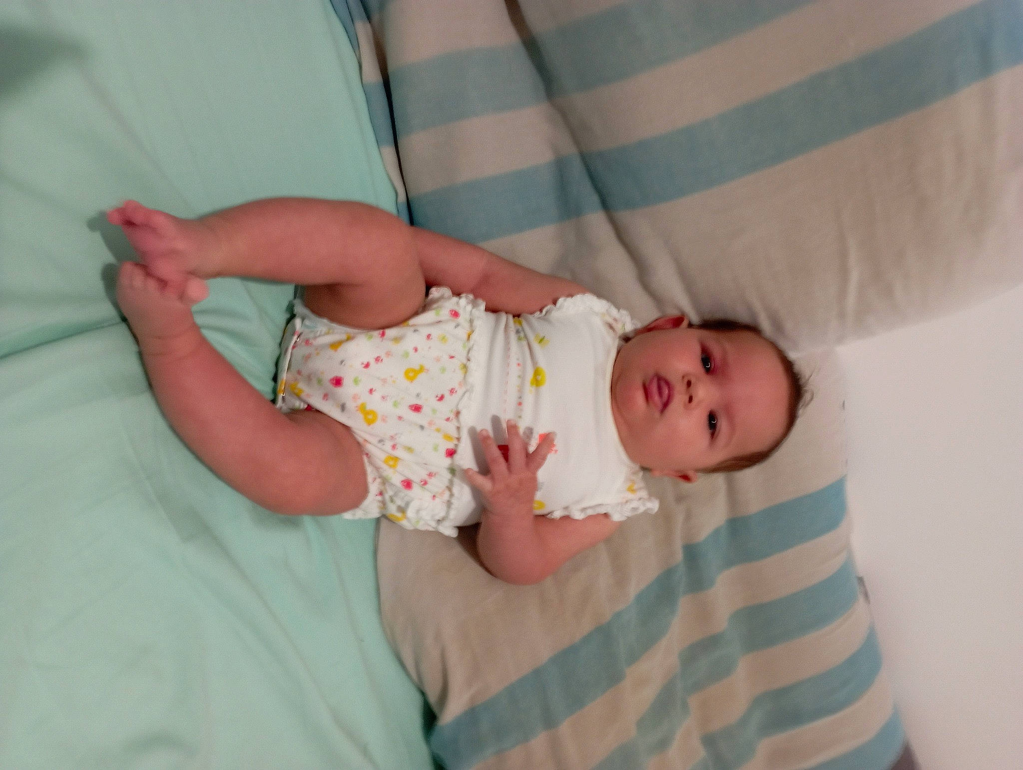 Ericka participe au concours pour gagner de l'argent avec cette photo : baby, baby_products, baby_toddler_clothing, child, comfort, dress, eye, face, finger, foot, human_body, leg, linens, pattern, person, room, sitting, skin, sleeve, textile