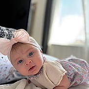 Heïly participe au concours pour gagner de l'argent avec cette photo : baby, blanket, blue_eyes, clothing, curious, cute, expression, face, headband, indoors, infant, knitwear, lying_down, natural_light, person, pink_bow, portrait, soft_texture, toddler, window