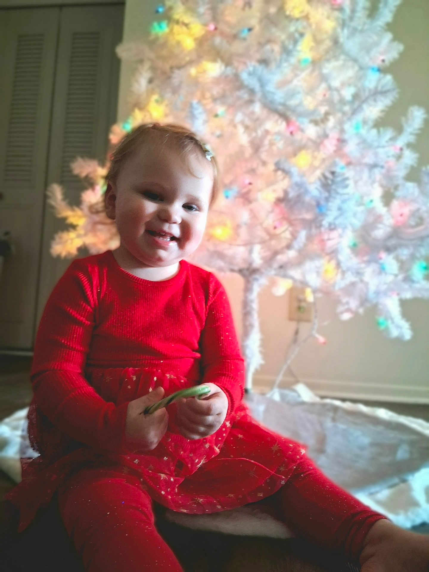 Mara joined the competition — help win amazing prizes! toddler, child, red_dress, candy_cane, christmas_tree, holiday, festive, indoor, smiling, happy, celebration, decorations, lights, seasonal, cute, portrait, sitting, festivity, joy, young_child