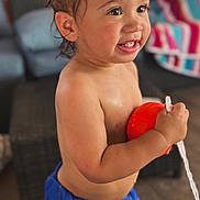 Messiah joined the competition — help win amazing prizes! toddler, child, smiling, indoor, blue_shorts, wet_hair, toy, red_toy, happy, cute, person, portrait, young_child, standing, home, furniture, blanket, colorful, bright, playful