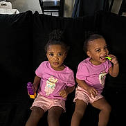 Amiah And Aminah joined the competition — help win amazing prizes! child, toddler, girl, pink_shirt, shorts, sitting, couch, black_couch, toy, blocks, smiling, playing, indoor, home, person, footwear, sandals, curly_hair, happy, cute