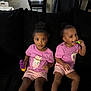 child, toddler, girl, pink_shirt, shorts, sitting, couch, black_couch, toy, blocks, smiling, playing, indoor, home, person, footwear, sandals, curly_hair, happy, cute