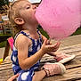 toddler, cotton_candy, outdoor, picnic_table, child, blue_outfit, pink_shoes, hand, food, sweet, summer, playful, fun, snack, park, grass, tree, side_profile, daytime, happy
