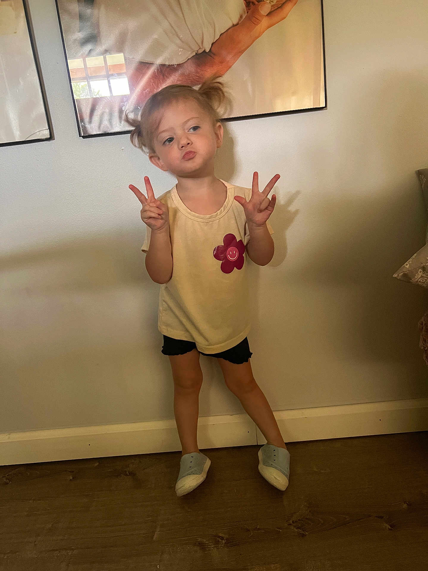 Madelyn joined the competition — help win amazing prizes! child, girl, pigtails, yellow_shirt, black_shorts, peace_sign, posing, indoor, wooden_floor, wall_art, framed_picture, smiling_flower, playful, standing, puckered_lips, shadow, casual_clothing, young, cute, expression