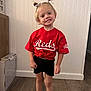 Madelyn joined the competition — help win amazing prizes! child, girl, smiling, pigtails, bows, red_jersey, shorts, barefoot, wooden_floor, indoor, wall_paneling, standing, happy, casual_clothing, portrait, young, person, home, cute, fashion
